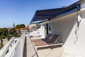 Un balcone con due lettini, una ringhiera bianca e vista libera sullo skyline della città.