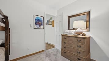 A hallway with a wooden dresser, a mirror, and a framed picture on the wall.
