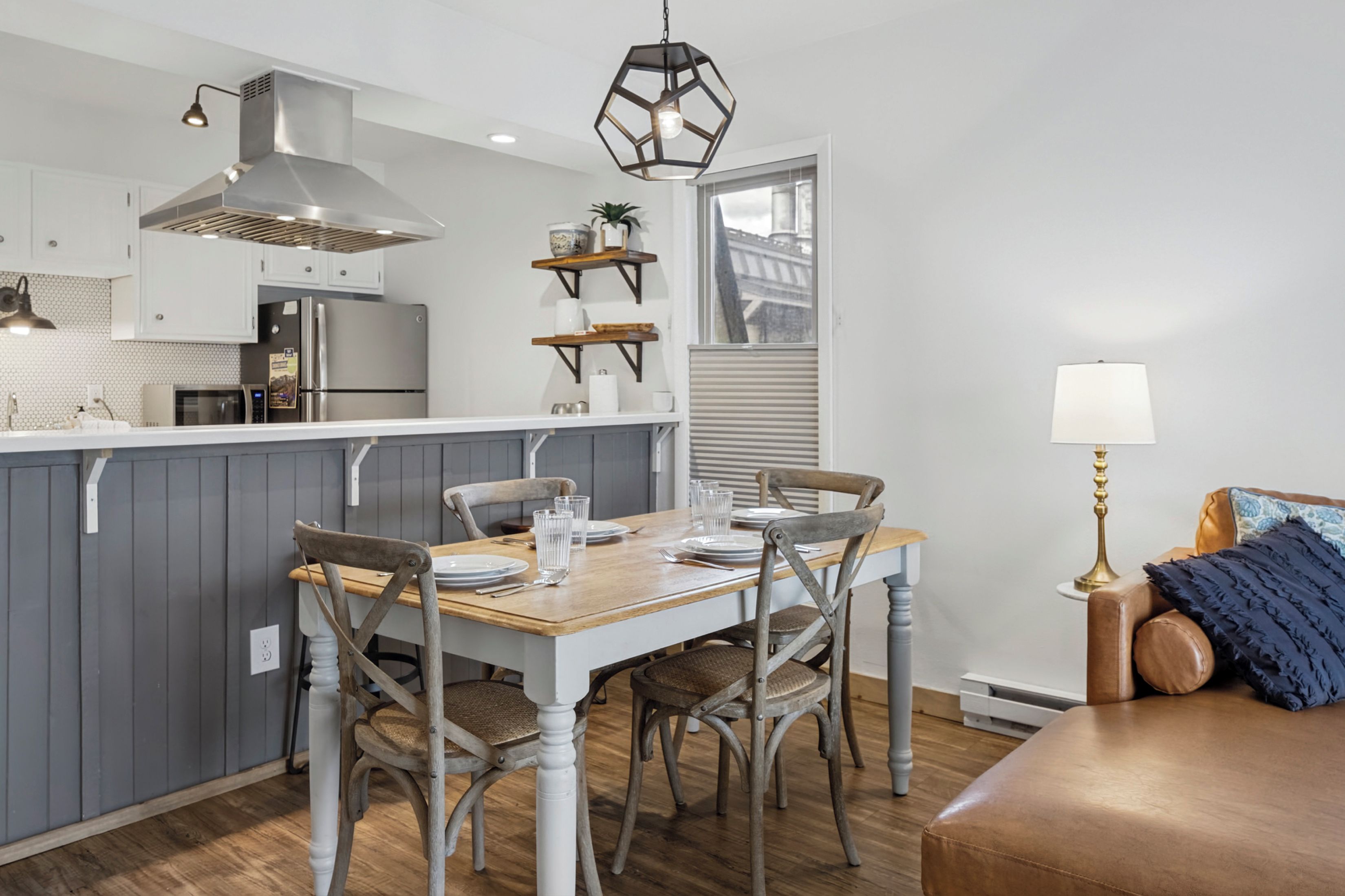 A modern kitchen with a central island, wooden chairs, and a dining table set for four.