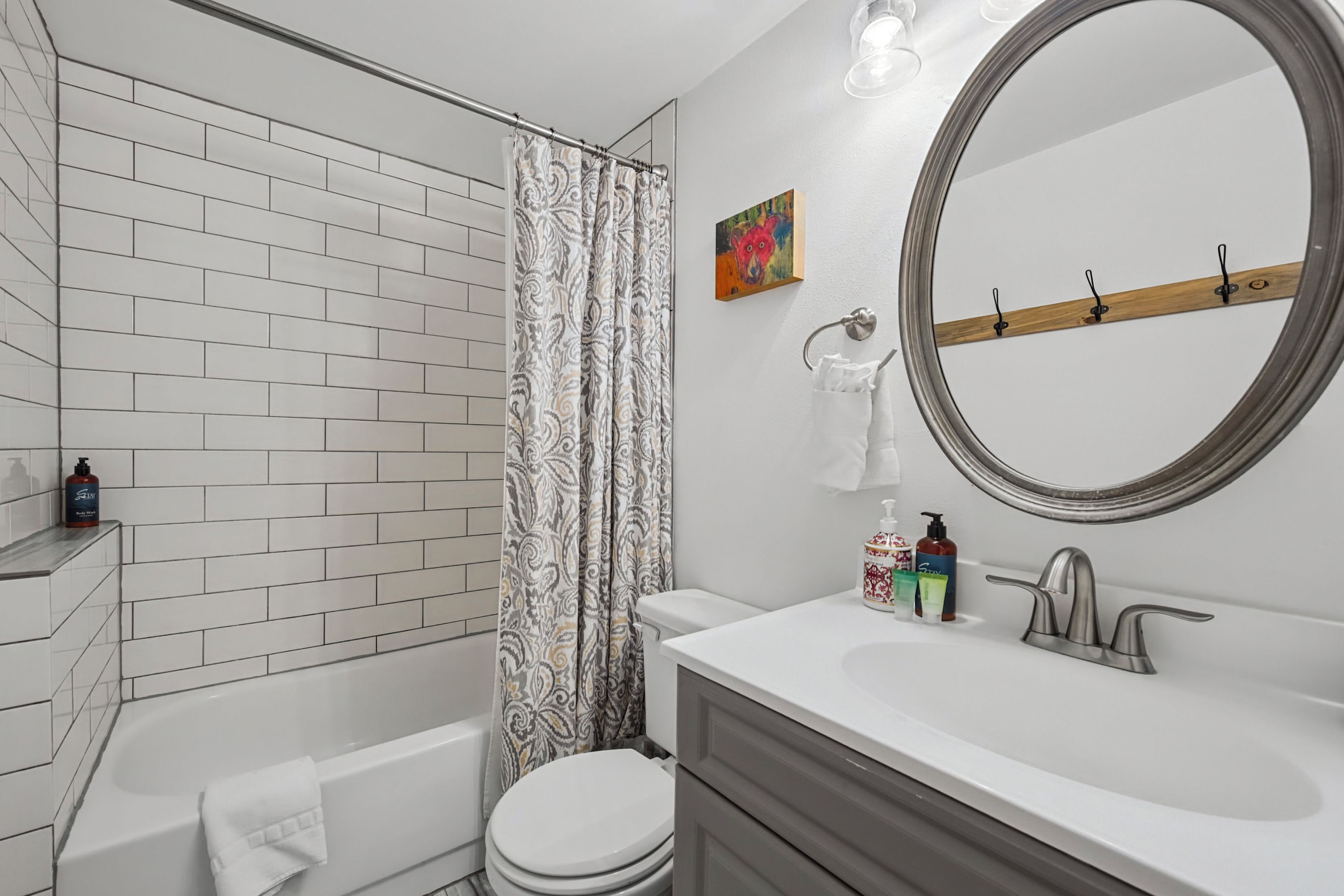 A bathroom with a white bathtub, a toilet, a vanity with a mirror, and a shower curtain.