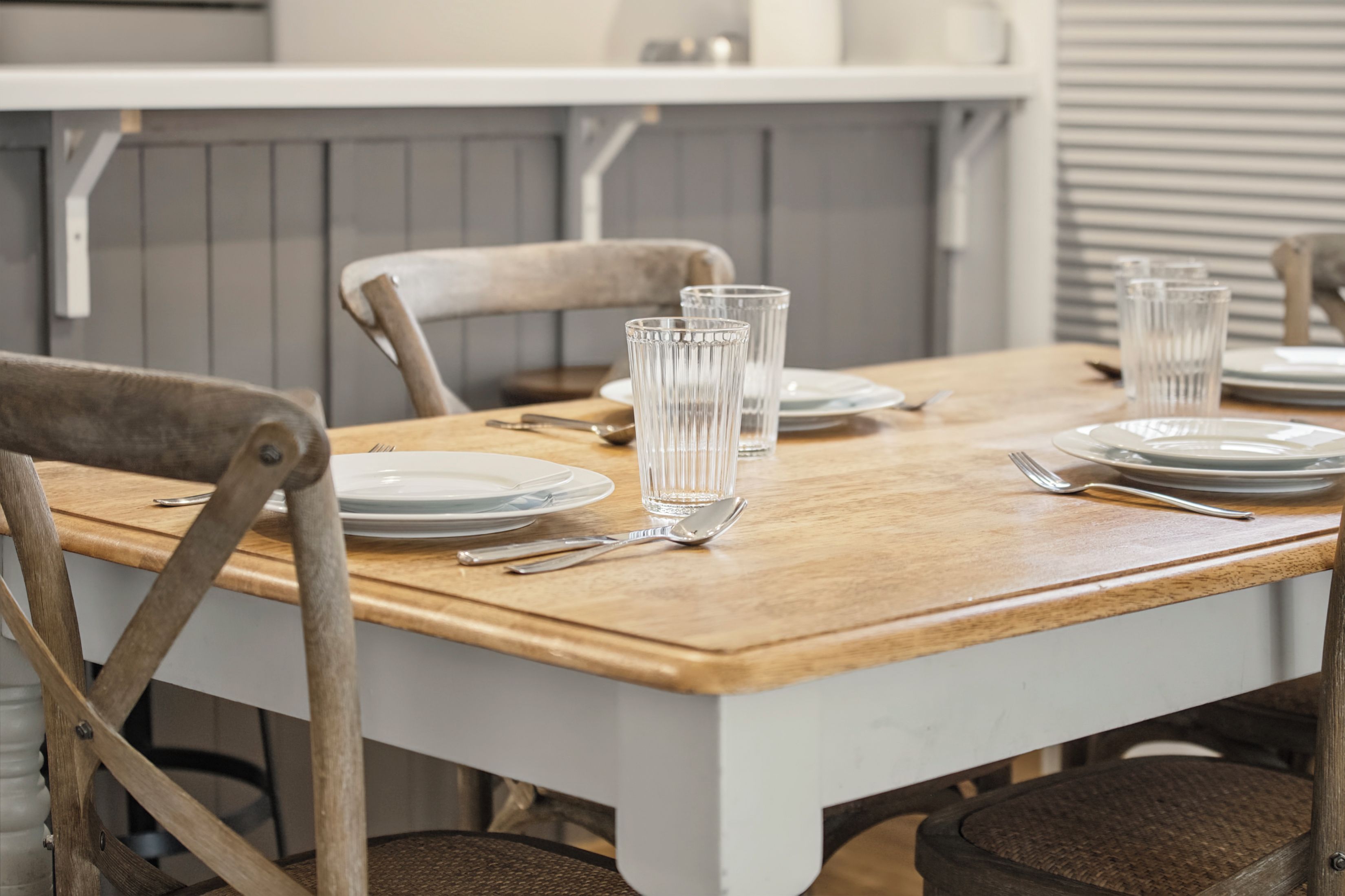A dining table set with plates, cutlery, and glasses, with chairs around it.