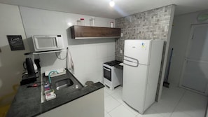 A compact kitchen with a microwave, stove, and refrigerator. - Porto Paradise, 300 meters from the sea. (Ipojuca)