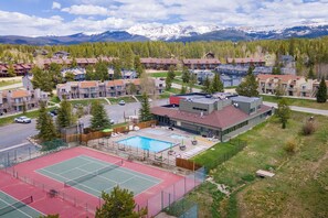 Een woongebied met een tennisbaan, zwembad en uitzicht op bergen.