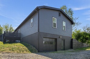 Une maison à deux étages avec un garage, une véranda et une allée gravillonnée.