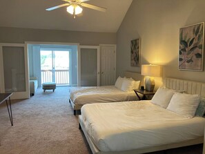 A bedroom with two beds, a ceiling fan, a nightstand with a lamp, and a view of the outdoors through a door. - 2 Lowcountry Lakehouse: Child & Pet Friendly! (North Charleston)