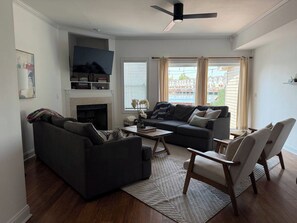 Una sala de estar con chimenea, dos sofás, una mesa de centro y un ventilador de techo.