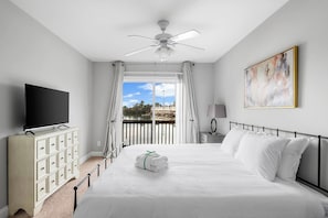 Una habitación de hotel con cama, televisión, escritorio, lámpara y un cuadro.