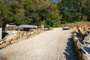 A gravel driveway leading to a parked car and a trailer with a sign. - Vacation Rental 2 with a Forest View Near Bayreuth (Mistelgau)