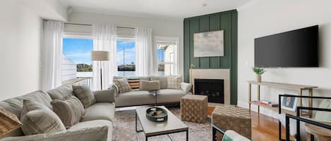 A modern living room with a sofa set, a coffee table, a fireplace, and a television mounted on the wall.