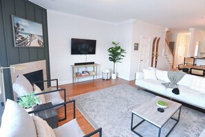 A modern living room with a sofa, coffee table, and a flat-screen TV mounted on the wall. - 1 Lowcountry Lakehouse: Child & Pet Friendly! (North Charleston)