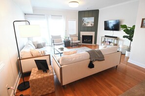 Uma sala de estar moderna com sofá, poltronas, mesa de centro e lareira.