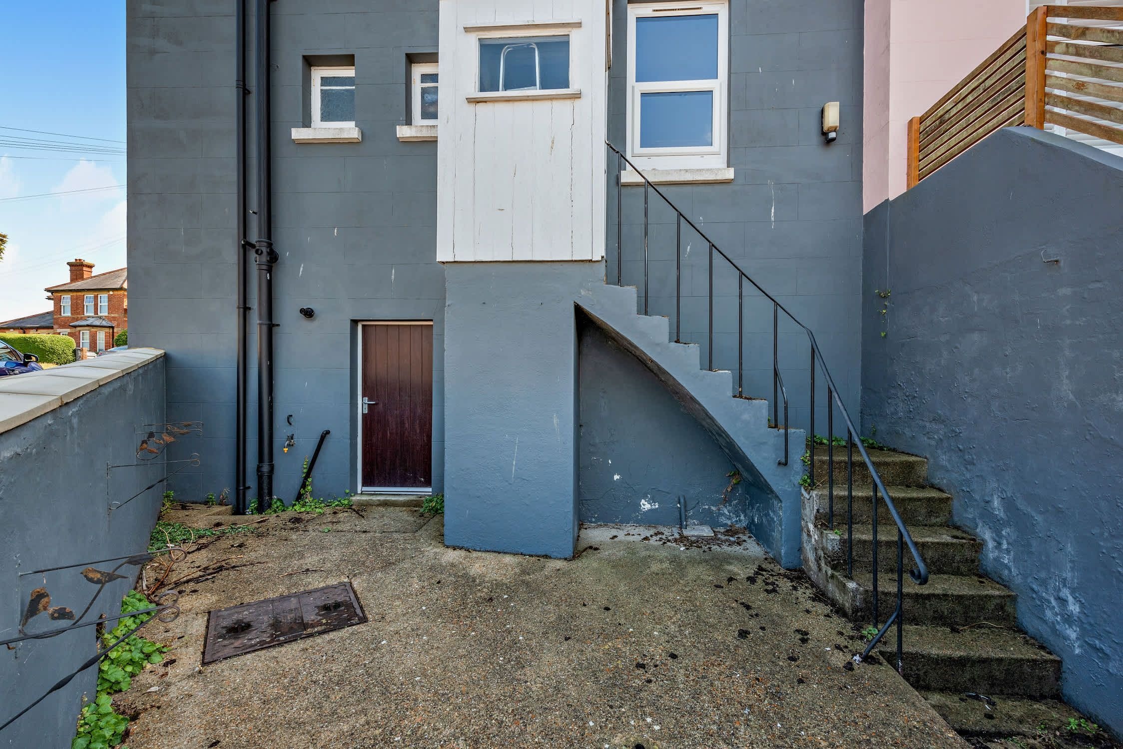 A narrow alleyway with a staircase leading to a building with a dark facade and a door.