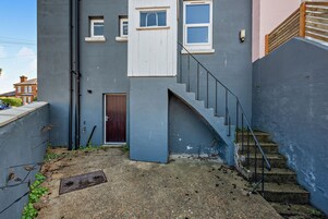 A narrow alleyway with a staircase leading to a building with a dark facade and a door.