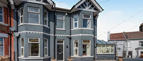 A two-story house with a bay window on the first floor and a dormer window on the second.