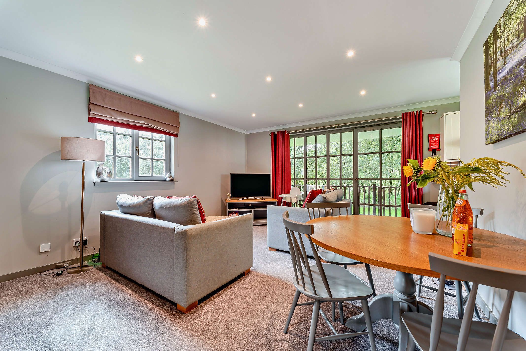 A modern living room with a sofa, TV, and dining area with chairs and a table.