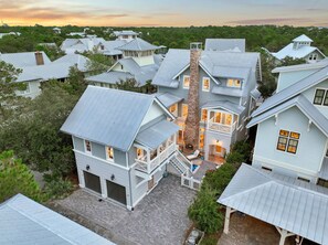Uma casa grande e de vários andares, com uma chaminé notável, várias janelas e um gramado bem cuidado.