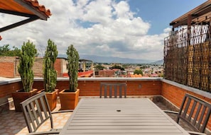 A rooftop terrace with a table and chairs, potted cacti, and a view of a cityscape. - Full House in Downtown (Terrace + Parking) (Oaxaca de Juárez)