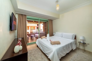 Une chambre d’hôtel avec un lit, un bureau, une télévision et une vue sur l’extérieur.