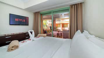Une chambre d’hôtel avec un lit, un téléviseur affichant « NETFLIX », un balcon avec vue et une commode en bois.
