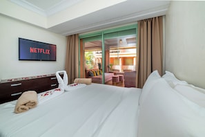 Une chambre d’hôtel avec un lit, un téléviseur affichant « NETFLIX », un balcon avec vue et une commode en bois.