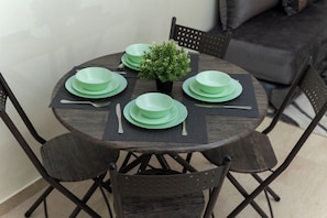 Une table de salle à manger ronde, surmontée d’une plante en pot, et entourée de six chaises.