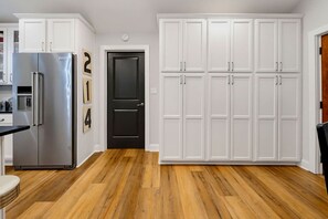 Una cucina con mobili bianchi, una porta nera e un frigorifero in acciaio inossidabile.