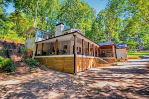 A modern house with a covered porch, a chimney, and a garage. - Lakefront Family Escape | Dock, Fire Pit & More (Flowery Branch)