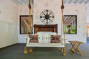 A room with a swing chair, a wooden table, and a compass wall decoration. - Lakefront Family Escape | Dock, Fire Pit & More (Flowery Branch)