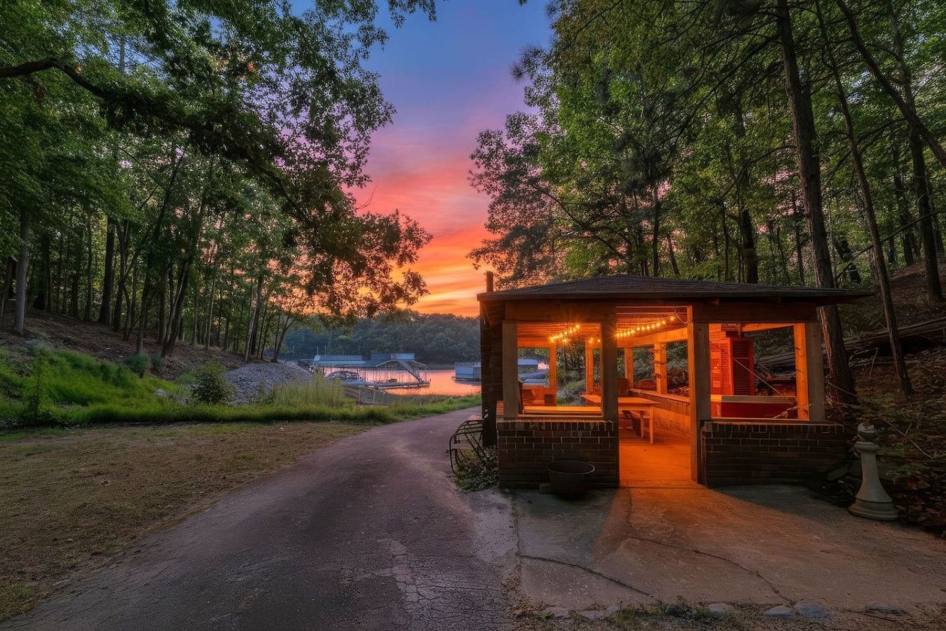 A cabin with a covered porch, a view of a lake, and a forested area.