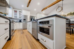 Una cucina moderna con mobili bianchi, elettrodomestici in acciaio inox e pavimento in legno.