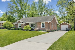 A two-story brick house with a front porch, a garage, and a well-maintained lawn. - Campus Edge Cottage - Serene 3-bedroom house in West Lafayette (West Lafayette)