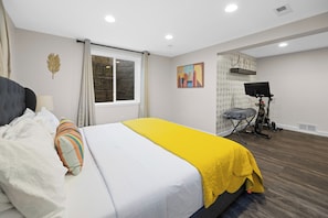 A bedroom with a bed, a window, a painting, and a treadmill. - Campus Edge Cottage - Serene 3-bedroom house in West Lafayette (West Lafayette)