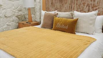 Un lit avec une couverture matelassée, une tête de lit en bois et un oreiller orné du mot «
Béni
».