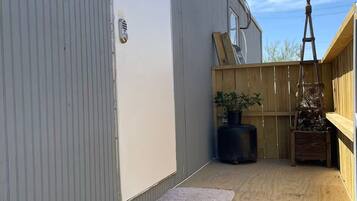 A covered outdoor area with a wooden deck, a potted plant, and a ladder.