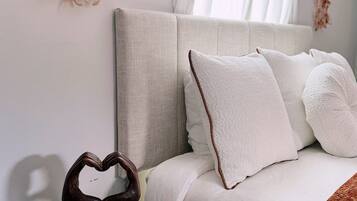 A bedroom with a bed, pillows, a wooden nightstand, and a decorative heart-shaped object.