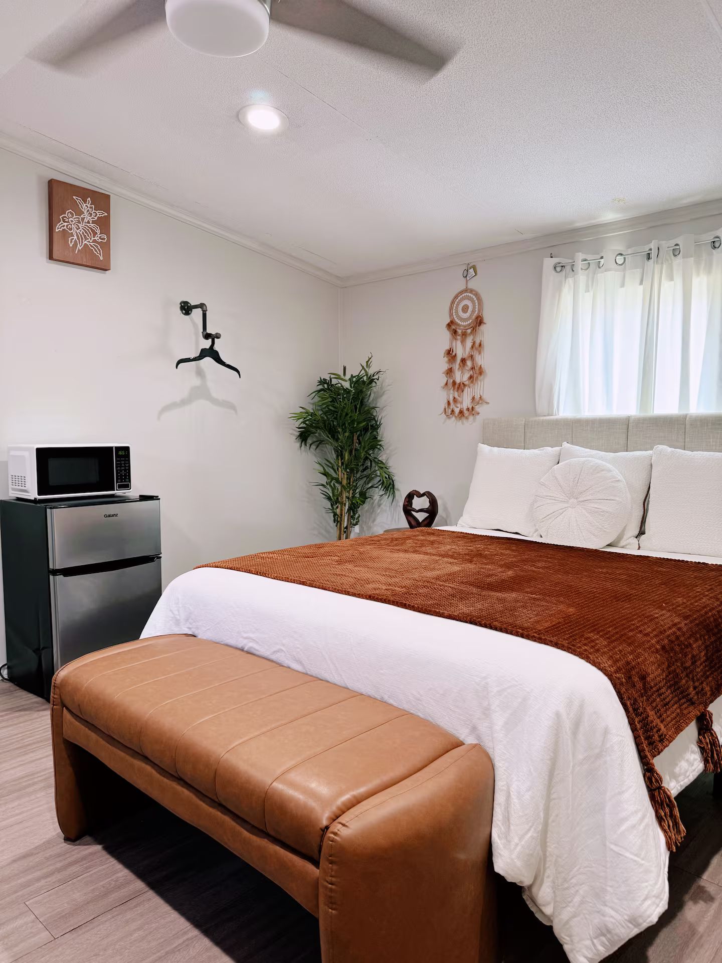 Quarto com cama, um banco, uma planta, um sonho apanhado e um guarda-roupa.