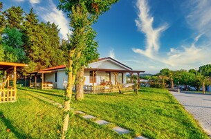 Una propiedad residencial con porche cubierto, césped y vistas del paisaje circundante.
