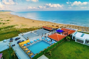 Een luchtfoto van een resort met een zwembad, strand en oceaan.