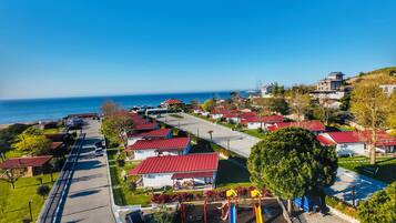 Zona residencial costera con casas, un parque infantil y una vista despejada del mar.