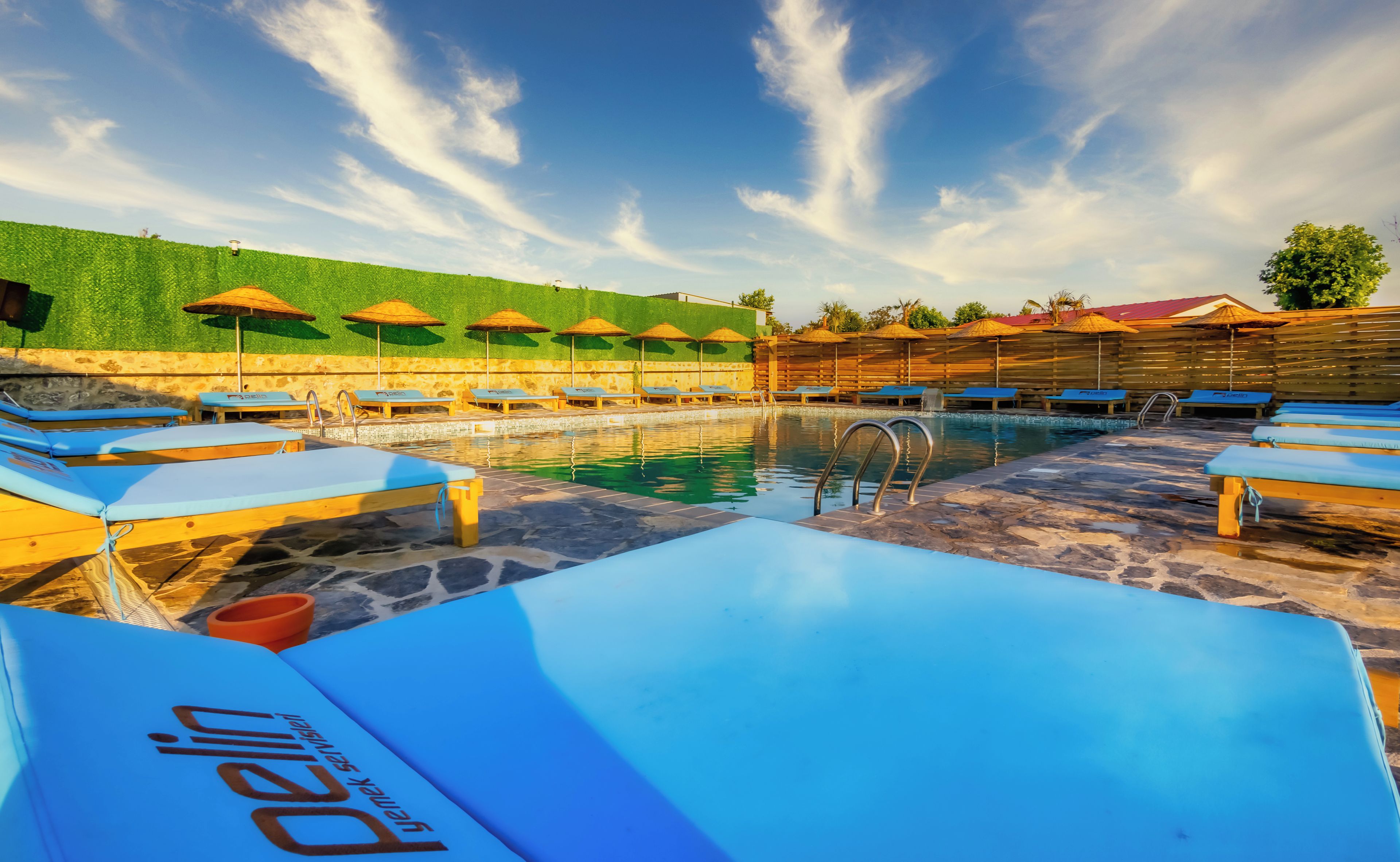 A swimming pool with lounge chairs and umbrellas, surrounded by a stone deck.
