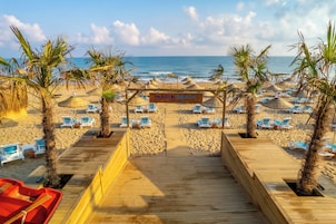 Una playa con una pasarela de madera que conduce a un letrero del Hotel Marin Beach.