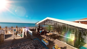 Een restaurant aan het strand met terras en uitzicht op zee.
