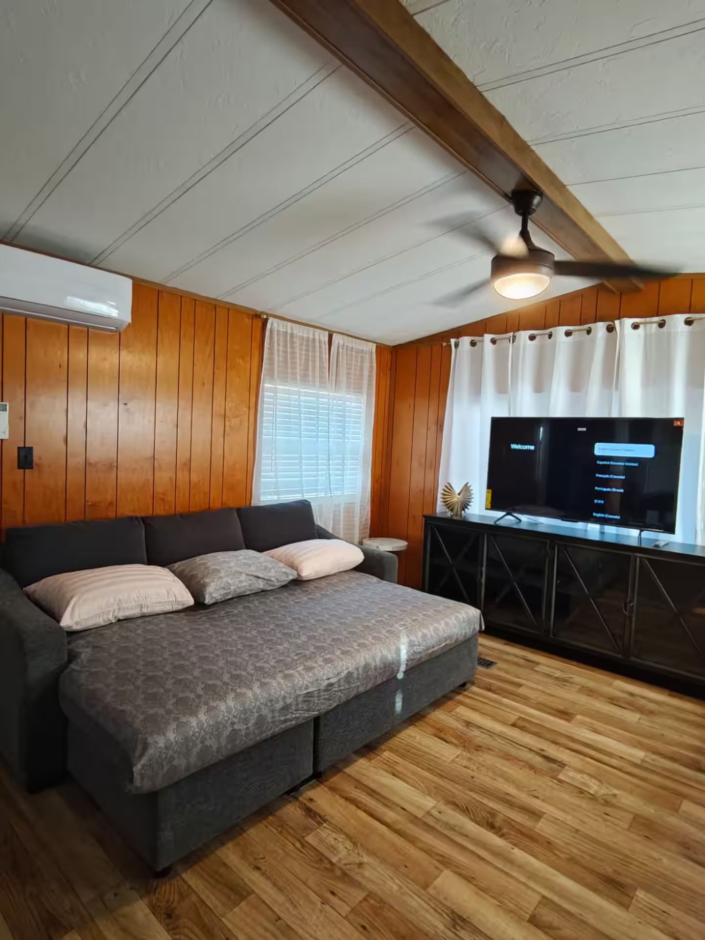 Une chambre avec un lit, une télévision et des panneaux de bois.