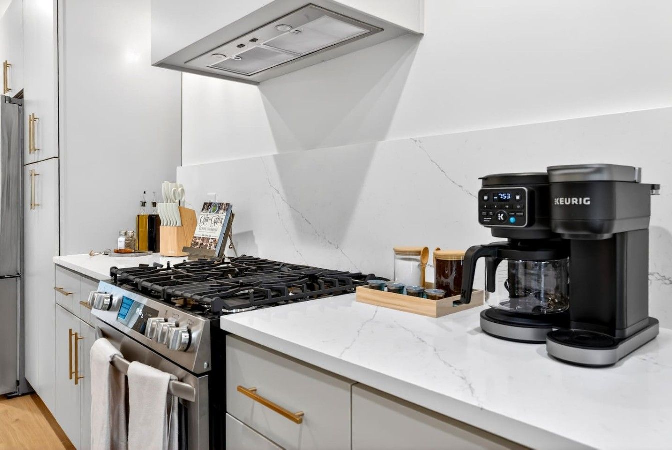 A modern kitchen with a gas stove, a coffee maker, and a marble countertop.