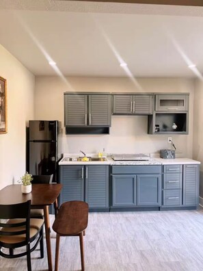 Una cocina moderna con armarios grises, un refrigerador de acero inoxidable y un comedor con mesa y sillas.