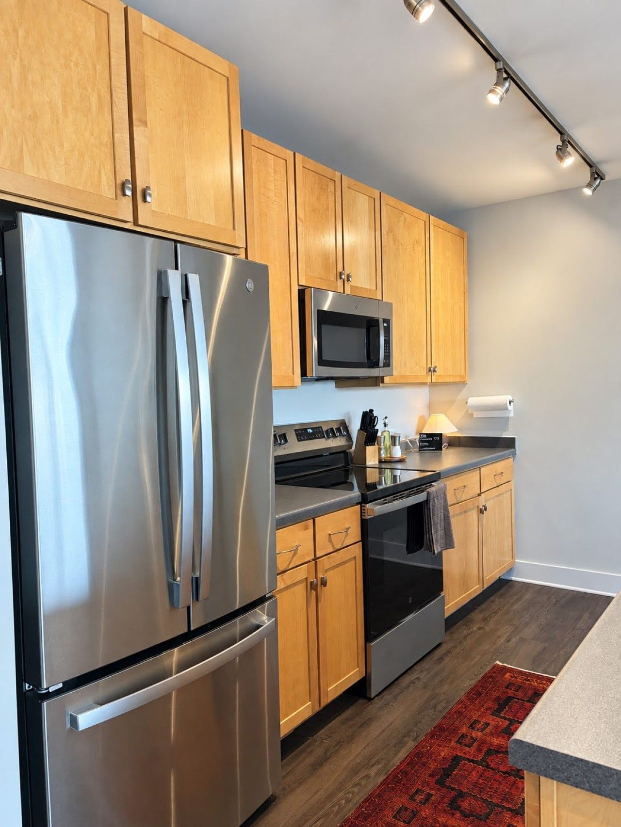 A modern kitchen with stainless steel appliances, wooden cabinets, and a black countertop.