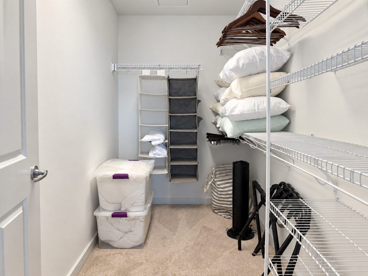 A storage closet with shelves, a hanging rack, and storage bins.