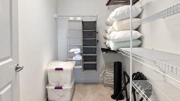 A storage closet with shelves, a hanging rack, and storage bins.