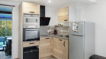 Een moderne keuken met houten kastjes, roestvrijstalen apparatuur en een inbouwoven.