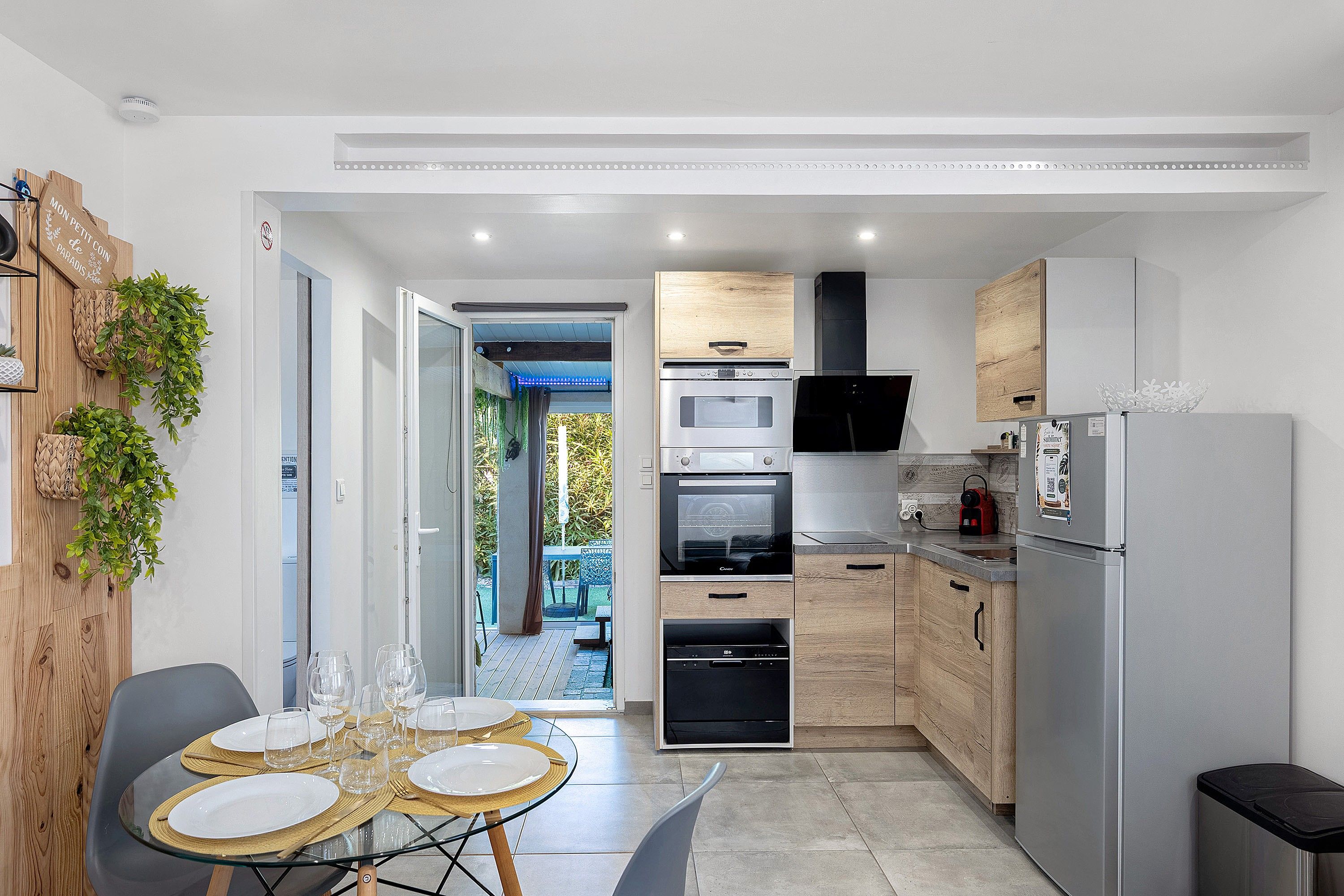 Une cuisine compacte dotée d’appareils électroménagers modernes, un coin repas avec une table en verre et une vue sur l’extérieur.